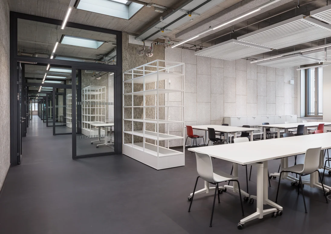 Weiße gefärbten Wände oder grauen Elemente aus Beton sowie der dunkle Fußboden geben den Räumlichkeiten im Inneren des Gebäudes einen schlichten und praktischen sowie multifunktionalen Look.