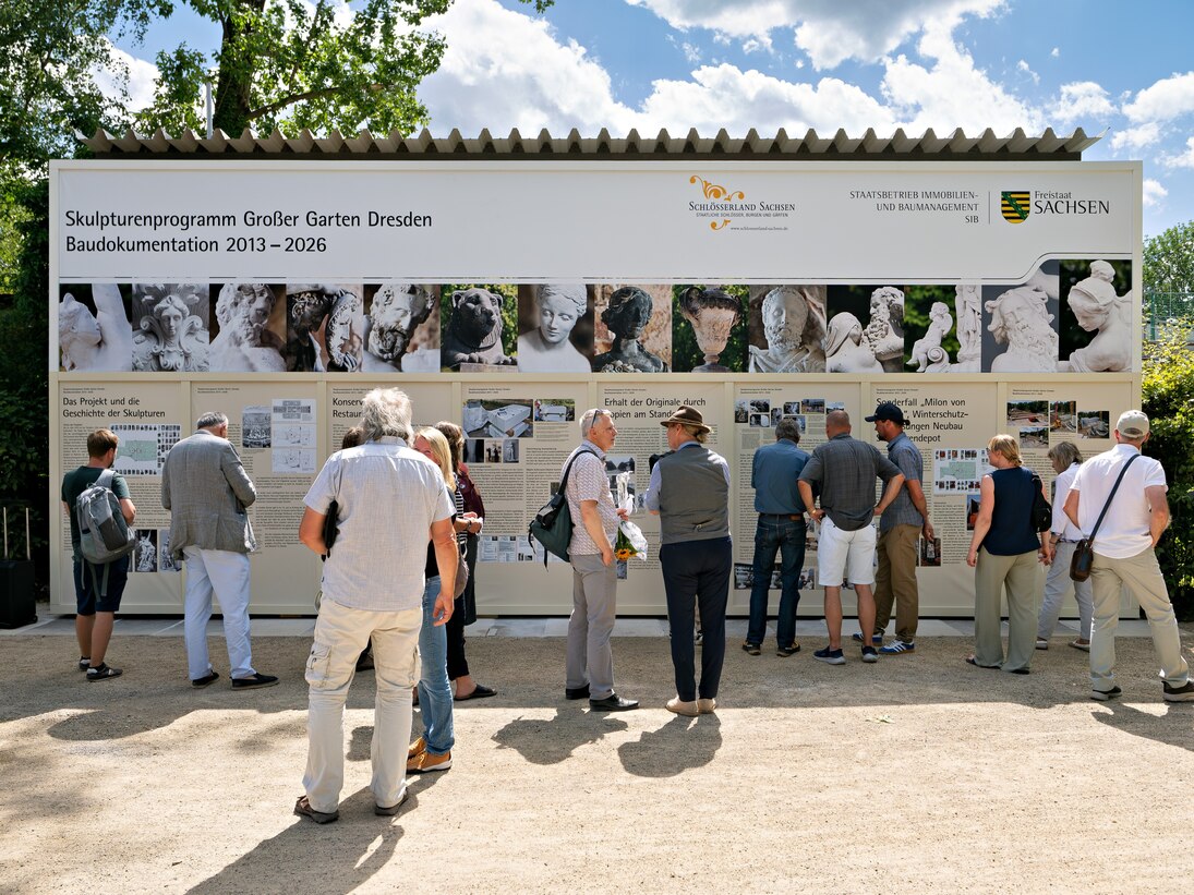 Menschen schauen sich Banner zum Skulpturenprogramm an