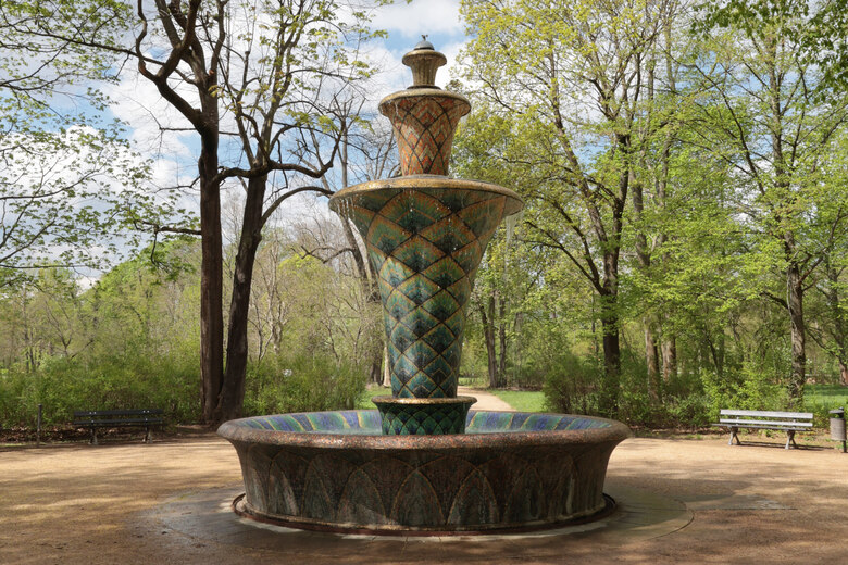Springbrunnen mit vier, übereinander angeordneter Becken, der mit hunderten kleinen, verschiedenfarbigen Mosaiksteinen verkleidet ist