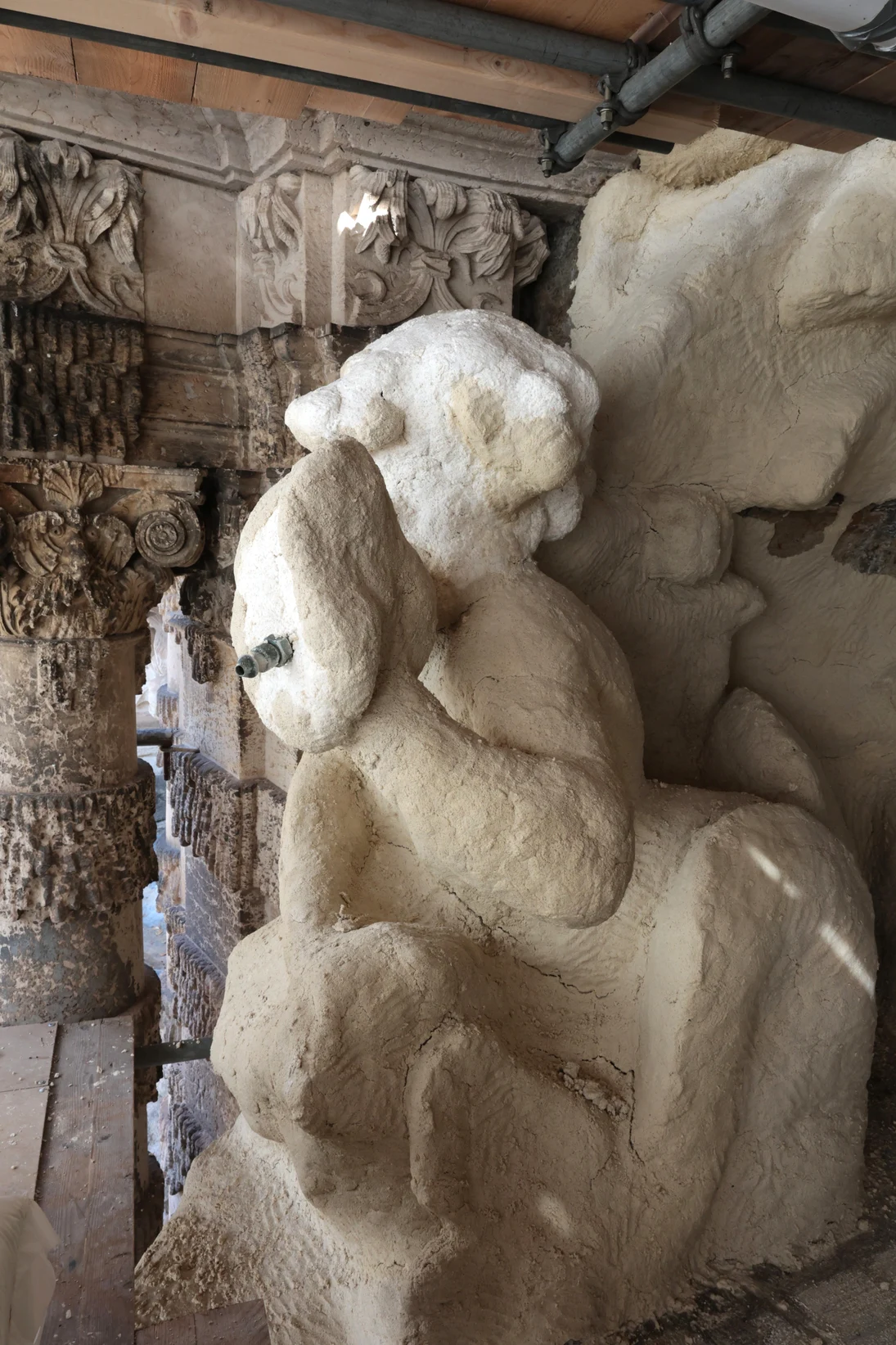 Eine Skulptur und die umliegenden Reliefs sind dick mit einer hellen Schicht beklebt, sodass die Formen nur grob zu erkennen sind.