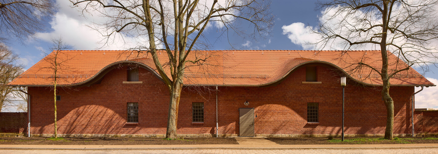 Die Außenansicht des Paddock 3 des Gestüts Graditz mit roter Bachsteinfassade und rotem Dach.