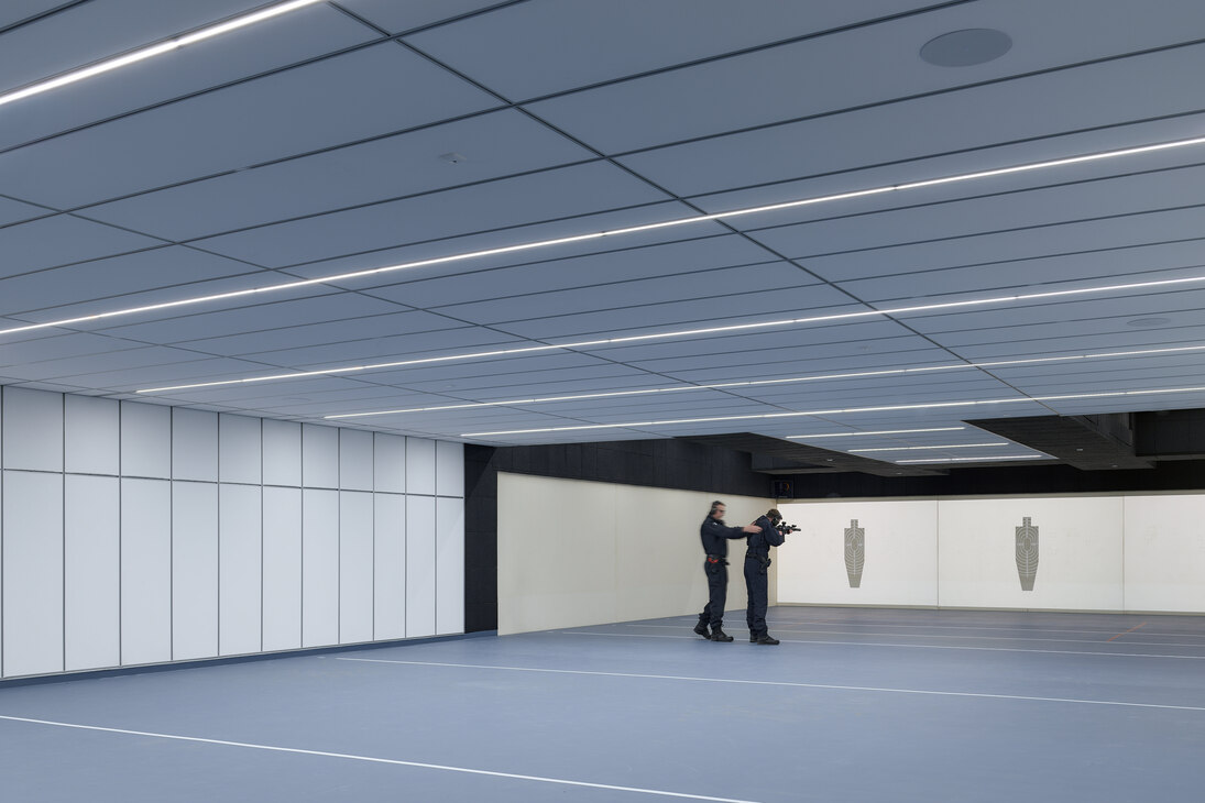 Die Decke und der Boden sind in langgezogene Kacheln in blauer Farbe untergliedert. An einem Ende der Anlage befinden sich Leinwände mit den virtuell simulierten Zielen.