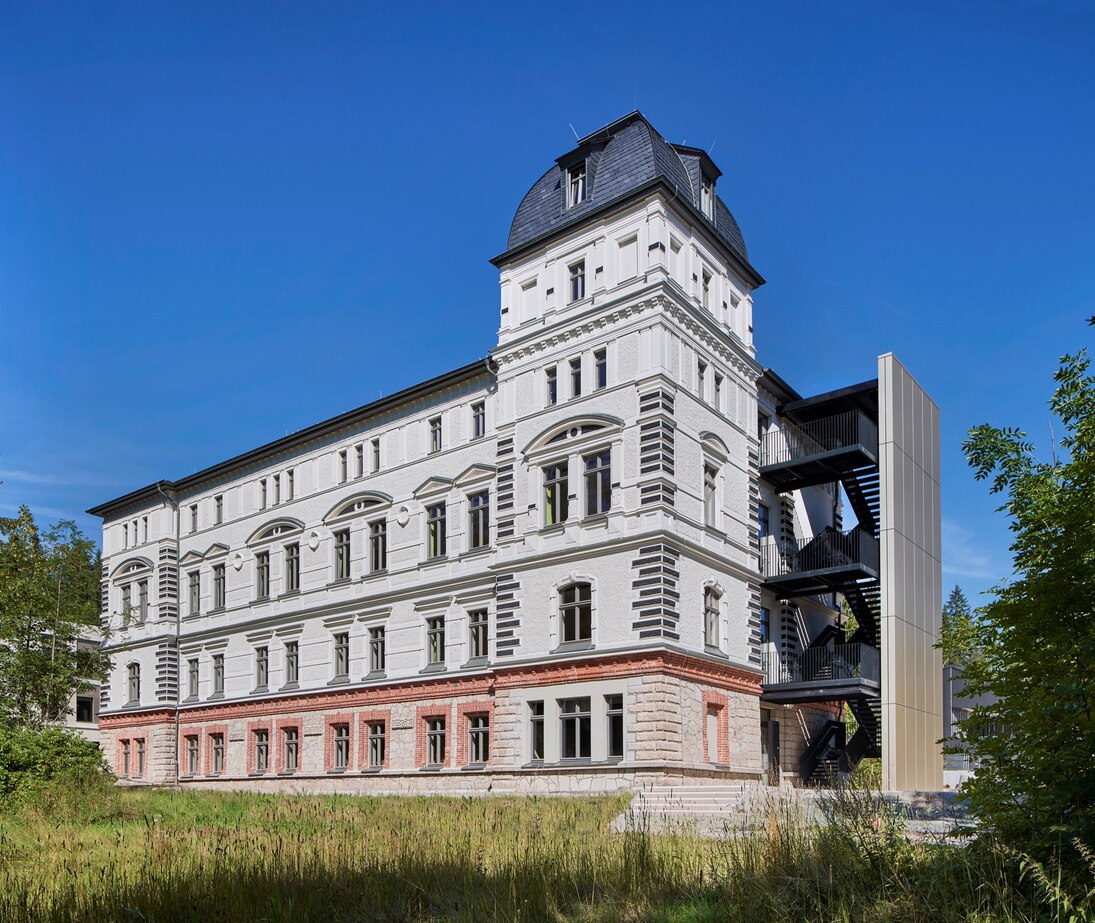 Eines der ursprünglichen, nun sanierten Gebäude jetzt als Wohnheim des Forstlichen Bildungszentrums mit Brandschutztreppe außen.