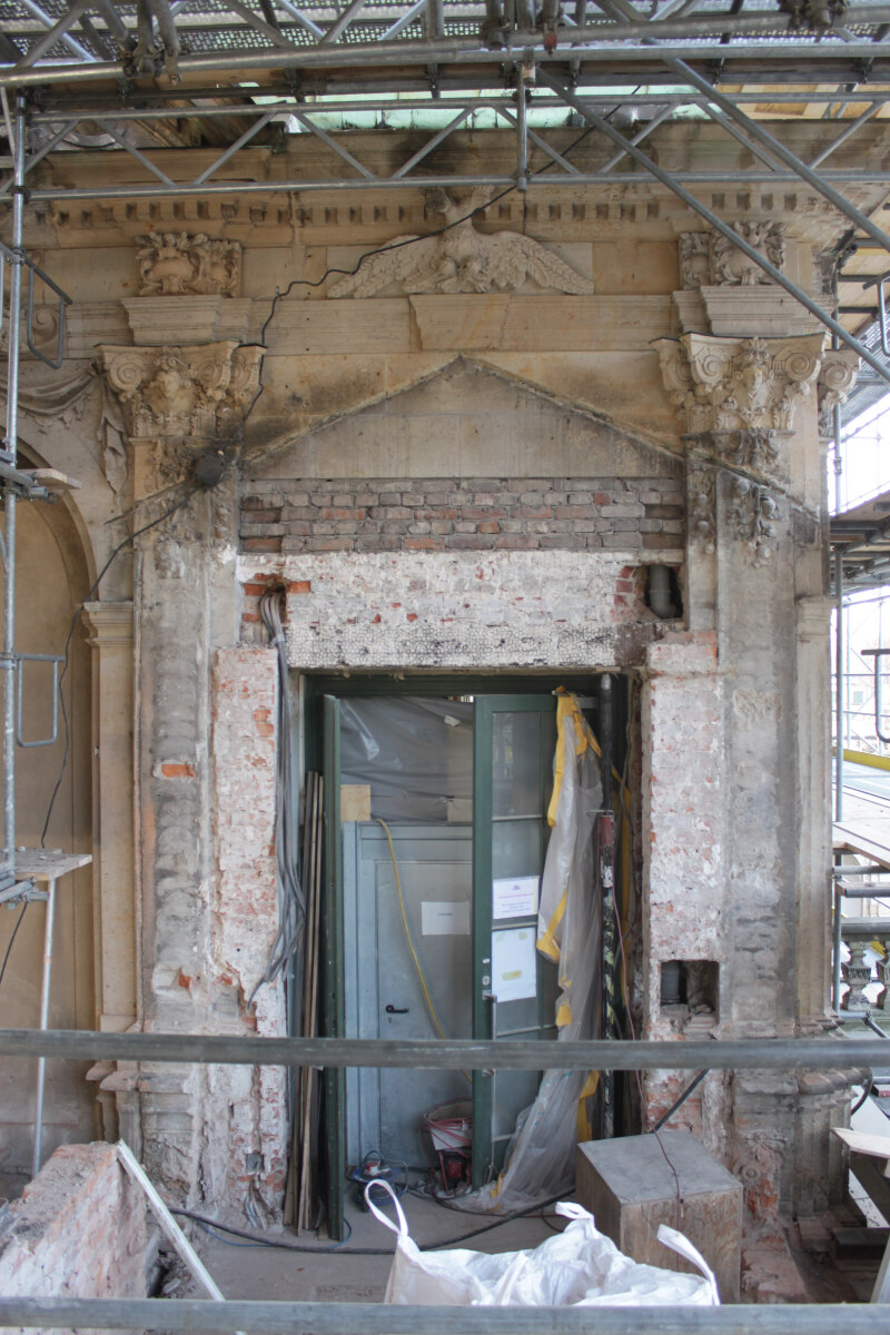 Nach Abbruch des alten Verbindungsbaus (der nicht aus der Erbauungszeit des Zwingers stammte) zeigte sich, dass dahinter der ursprüngliche Fassadenschmuck nicht mehr vorhanden war.