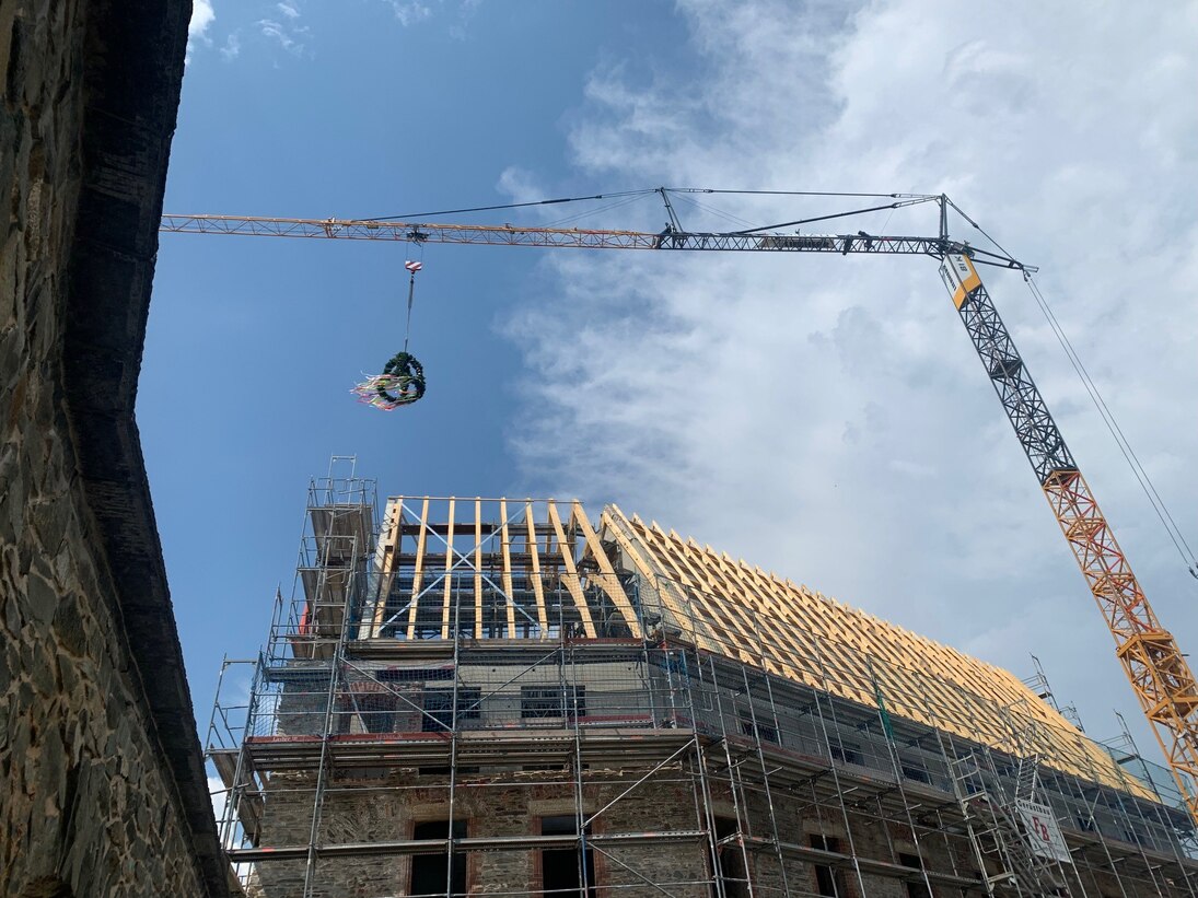 Die Richtkrone schwebt über dem Neubau. Der 62 Grad steile Dachstuhl erhält eine Schieferdeckung.