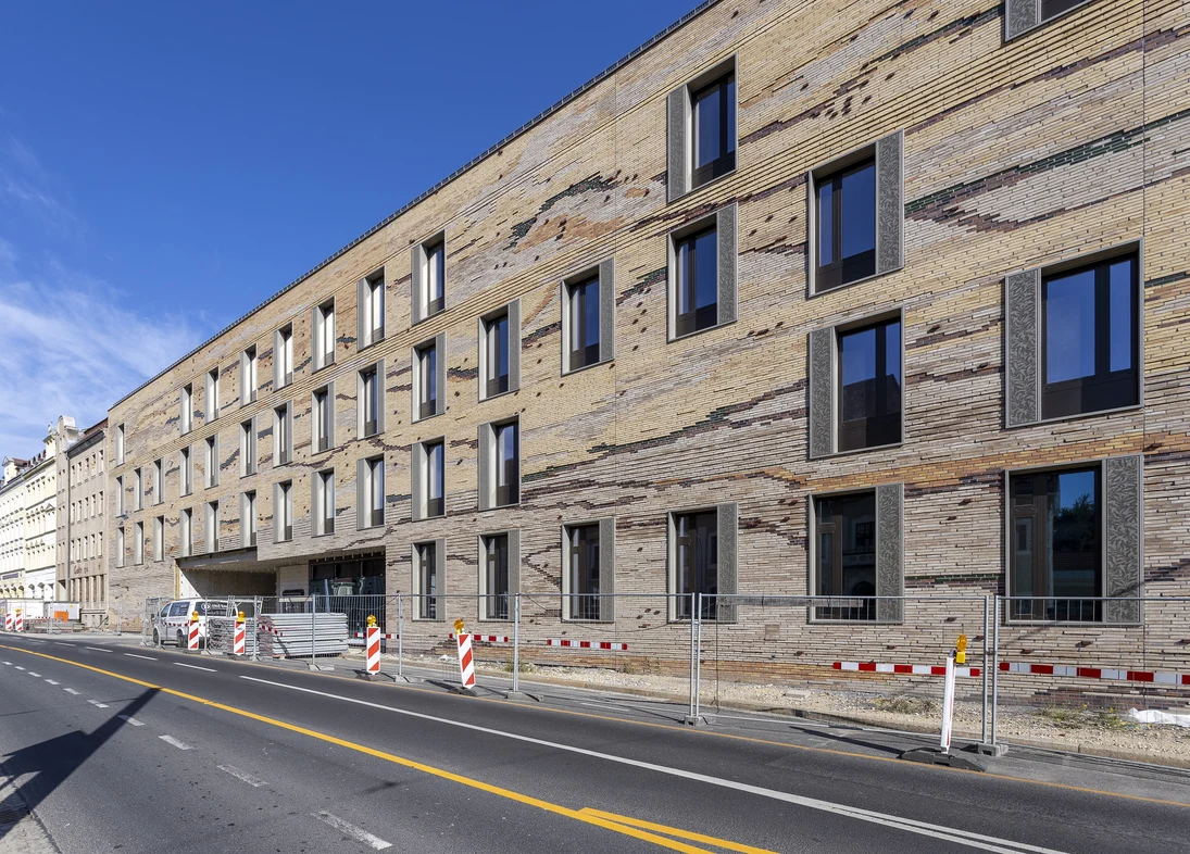 Zu sehen ist die Fassade des neuen Senckenberg-Campus G&ouml;rlitz von der Bahnhofstra&szlig;e Ecke Jakobstra&szlig;e aus. Sie ist mit lehmfarbenen Klinkern verkleidet, die optisch durch Farbunterschiede einen Querschnitt durch Sedimentgestein darstellen. (Ansicht 1)