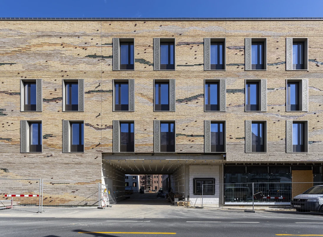 Zu sehen ist die Fassade des neuen Senckenberg-Campus G&ouml;rlitz von der Bahnhofstra&szlig;e Ecke Jakobstra&szlig;e aus. Sie ist mit lehmfarbenen Klinkern verkleidet, die optisch durch Farbunterschiede einen Querschnitt durch Sedimentgestein darstellen. (Ansicht 2)
