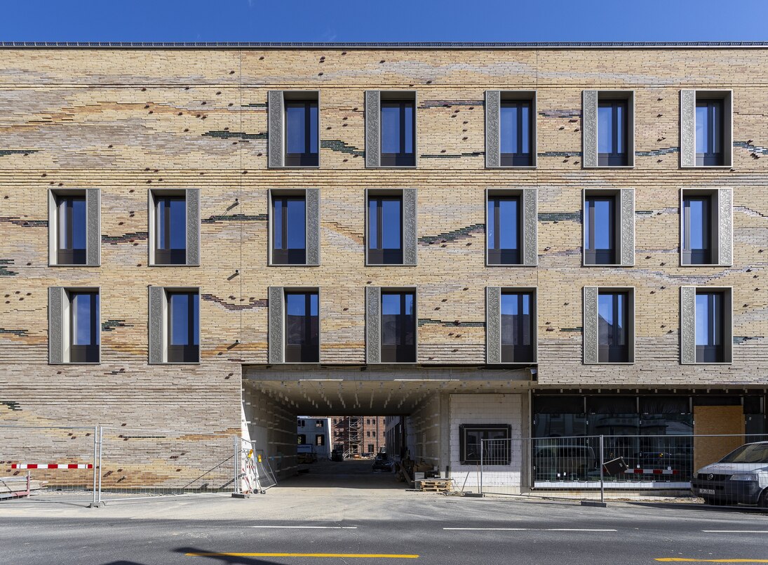 Zu sehen ist die Fassade des neuen Senckenberg-Campus Görlitz von der Bahnhofstraße Ecke Jakobstraße aus. Sie ist mit lehmfarbenen Klinkern verkleidet, die optisch durch Farbunterschiede einen Querschnitt durch Sedimentgestein darstellen. (Ansicht 2)